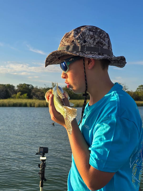 Young angler giving a small bass a kiss before release at Lake Bastrop
